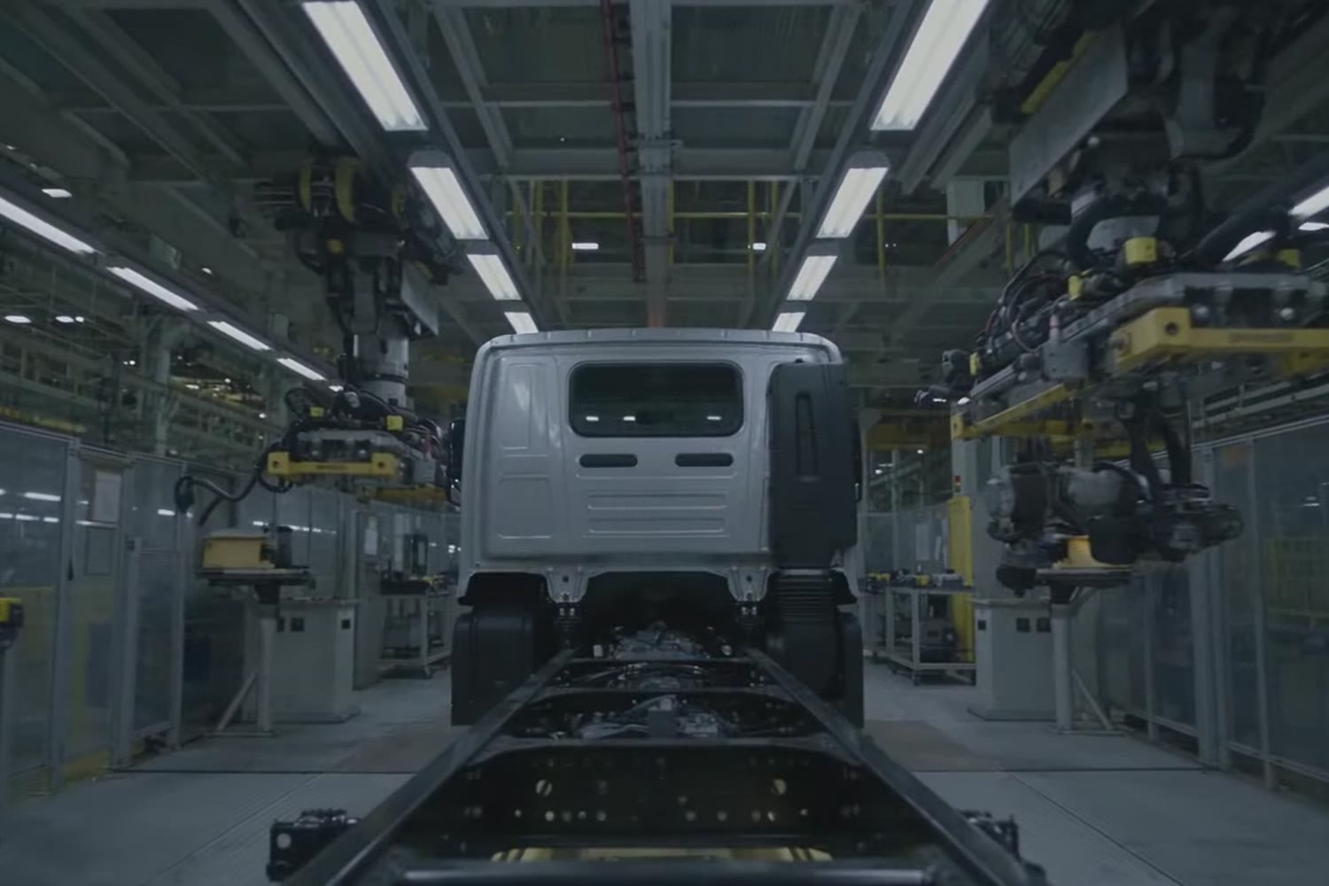 A truck cab on an assembly line between robot arms, illustration